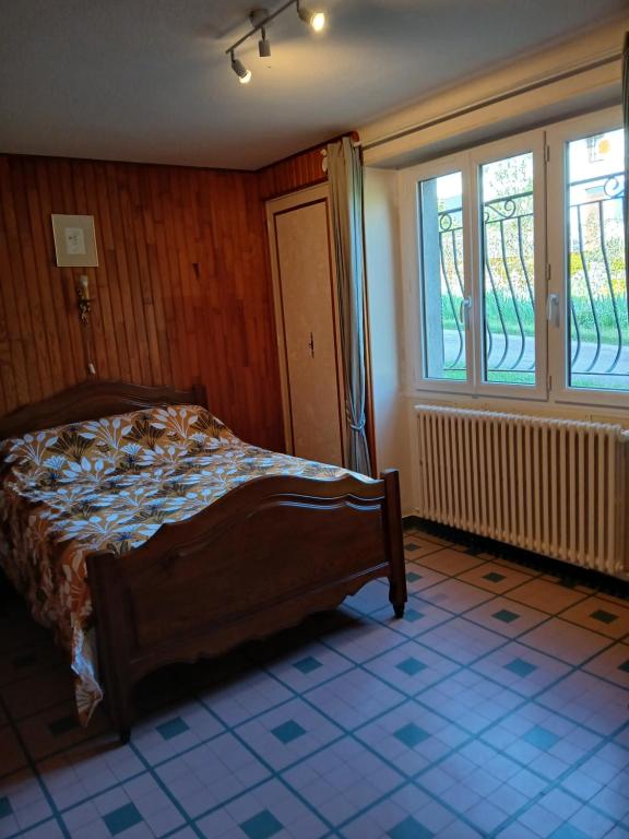 a bedroom with a bed in a room with windows at Gite les Tulipes in Liernais
