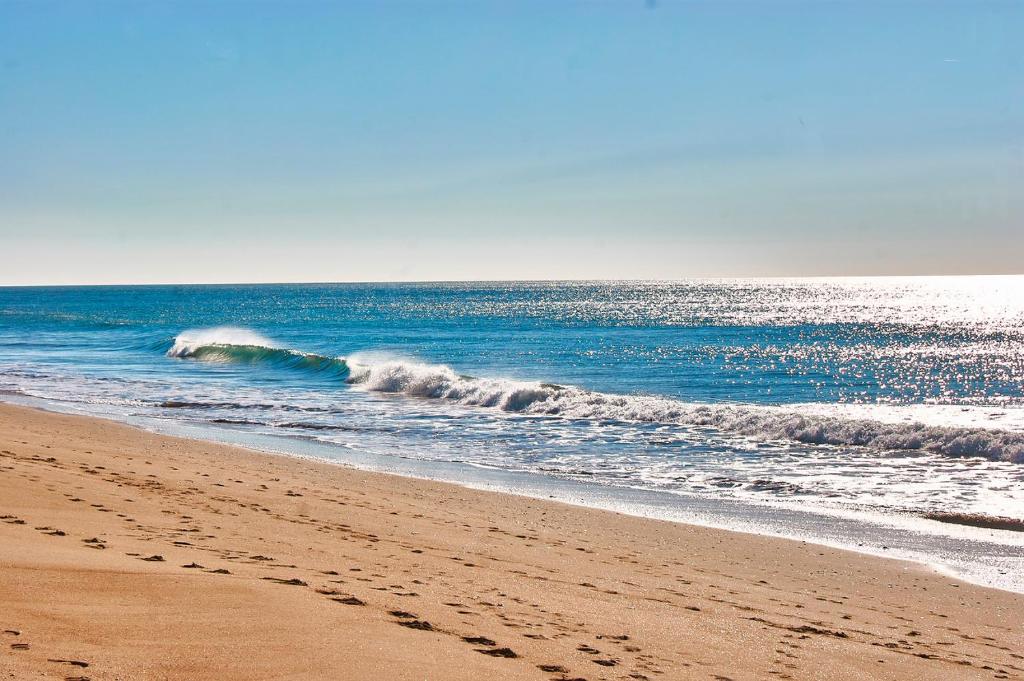 a wave in the ocean on a sandy beach at Chalets Paraíso Playa de Mazagón Con Vistas al Mar in Mazagón