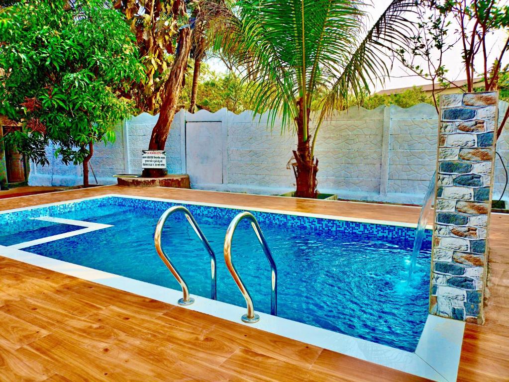 a large swimming pool in a yard with trees at River Garden Guest House in Jambhulpāda