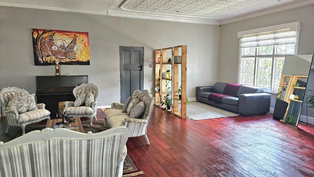 a living room with chairs and a couch and a piano at Jacaranda Escape in Pretoria