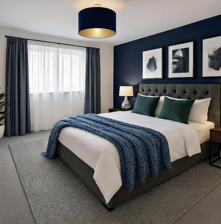 a bedroom with a large bed with a blue wall at Your Versatile Luxury - Space for All- Sleeps 10 in Bedford