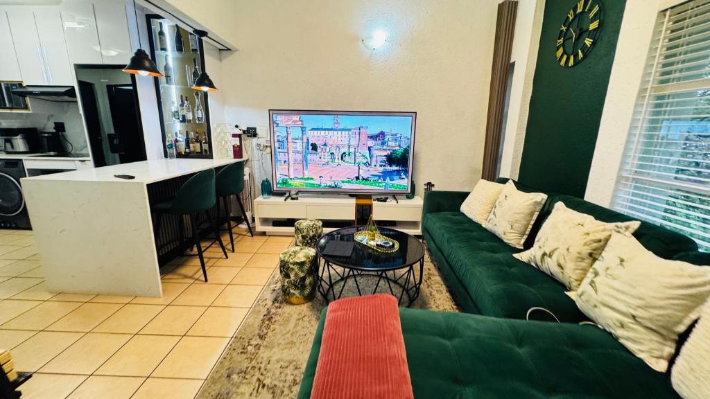 a living room with a green couch and a kitchen at The Urban Nest in Nelspruit