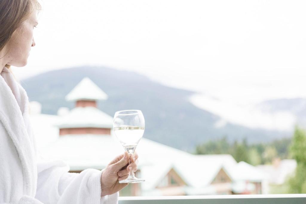 a woman sitting at a table with a glass of wine at Summit Lodge Boutique Hotel Whistler in Whistler