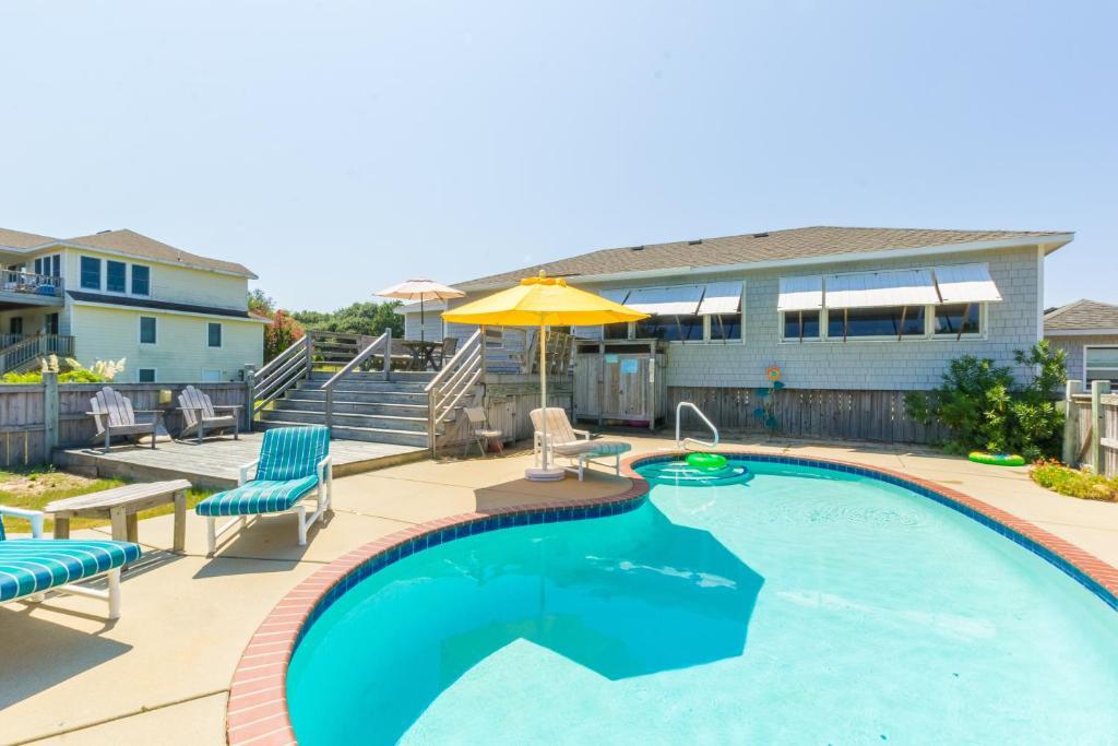 a swimming pool with chairs and an umbrella at 4601 - Sandy Bluff in Southern Shores