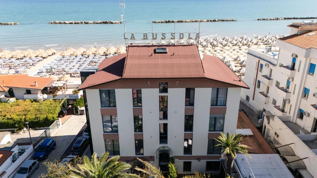 a building with a red roof next to a beach at Hotel La Bussola in Ortona