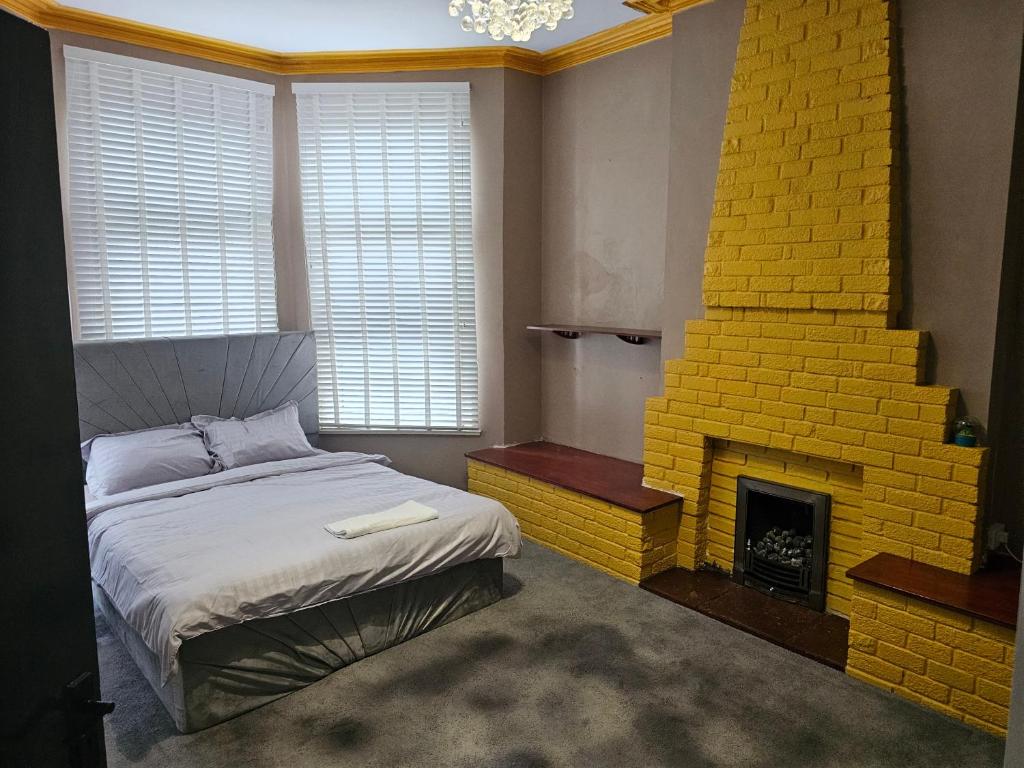 a bedroom with a bed and a yellow brick fireplace at M4 Victoria Hub in Newport