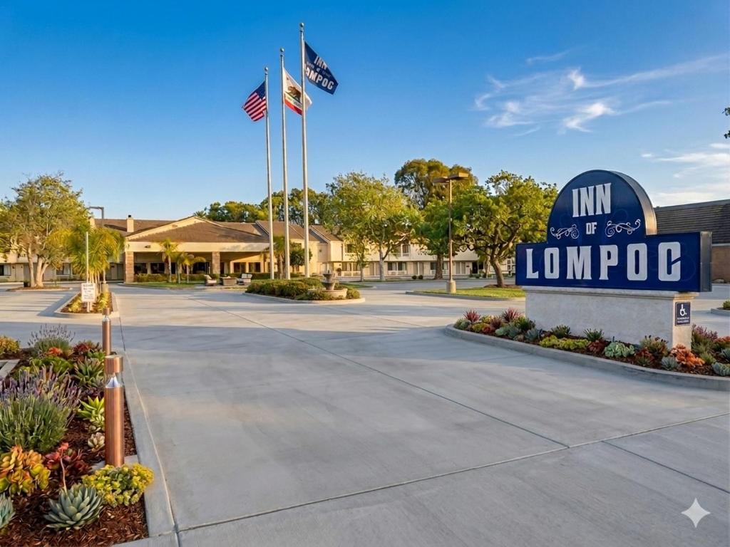 a sign for the inn of lompoc with two flags at Inn of Lompoc in Lompoc