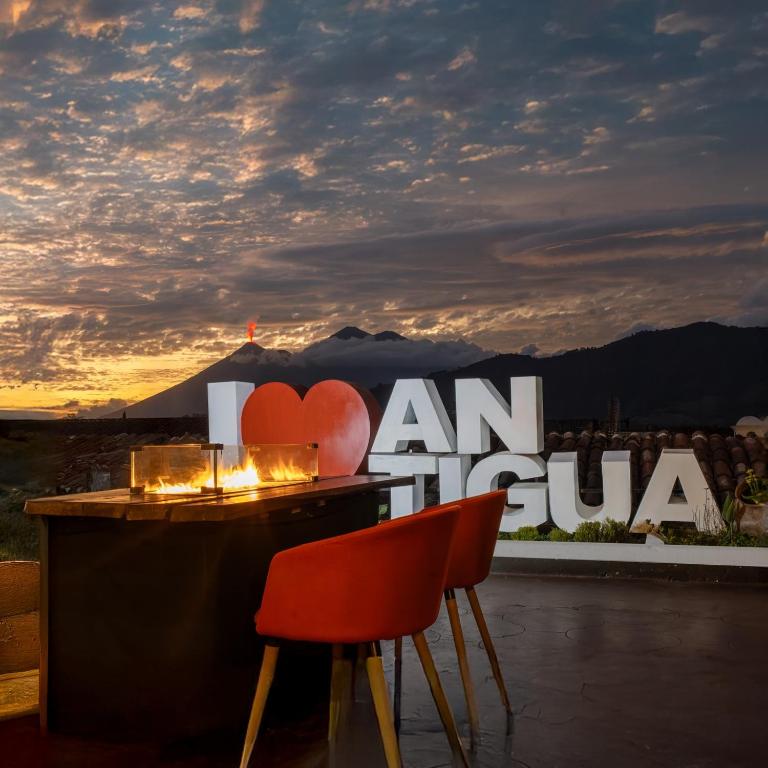 a bar with two red chairs and a sign that saysanulum at El Carmen Hotel in Antigua Guatemala
