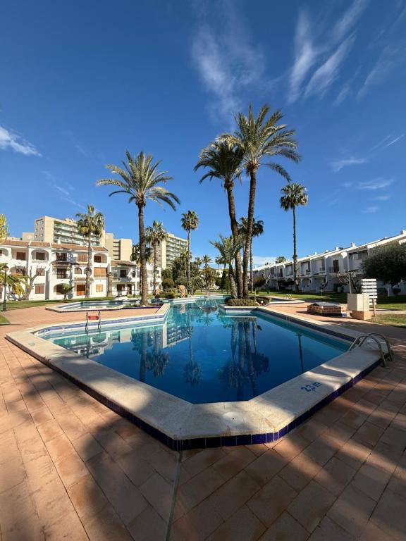 a swimming pool with palm trees and buildings at Club aldeas de taray in San Javier