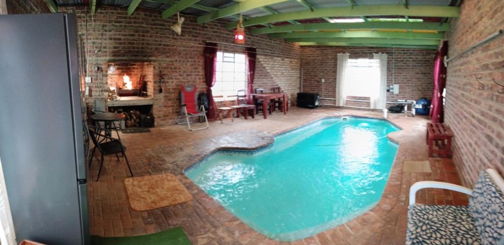 a large swimming pool in a room with a brick wall at IVCA Cottage in Addo