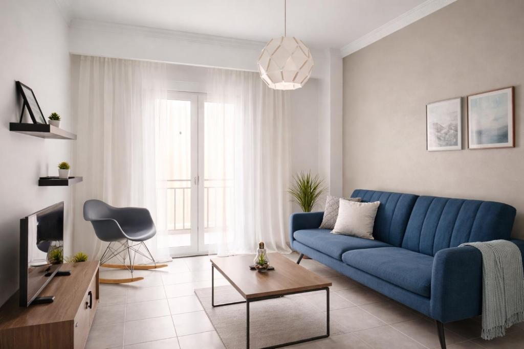 a living room with a blue couch and a tv at Midway Point Apts in Heraklio