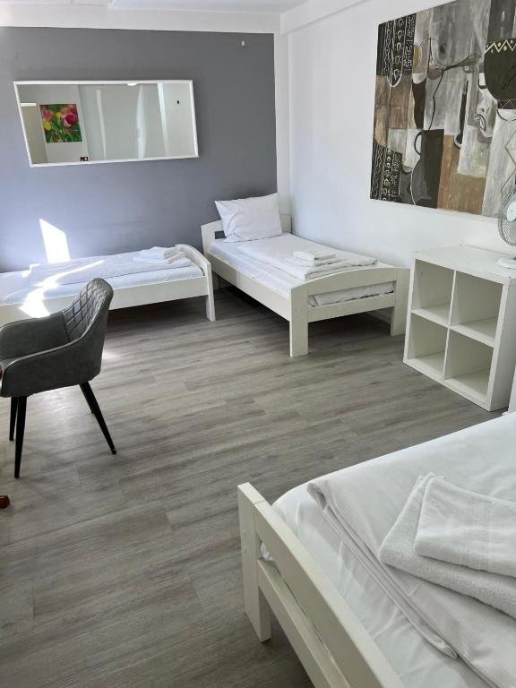 a bedroom with two beds and a chair and a mirror at Pension Passion Julie in Berlin