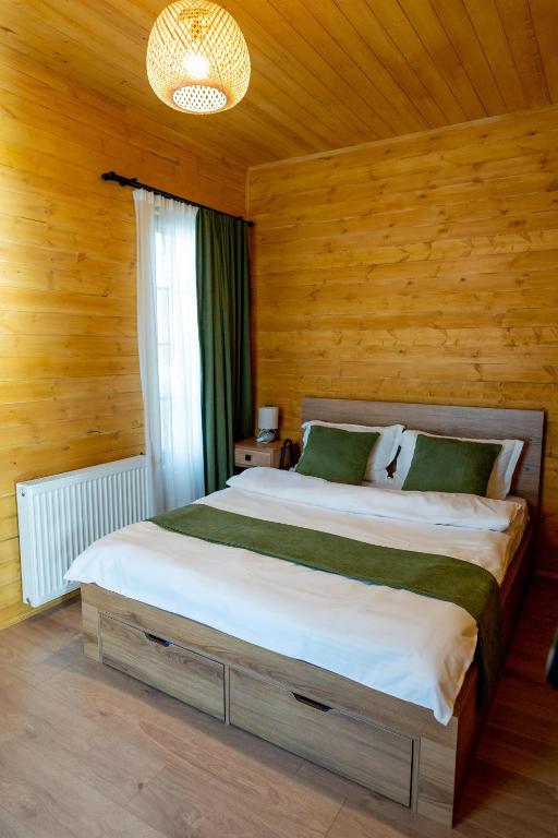 a large bed in a room with wooden walls at Natural cottage in Saguramo