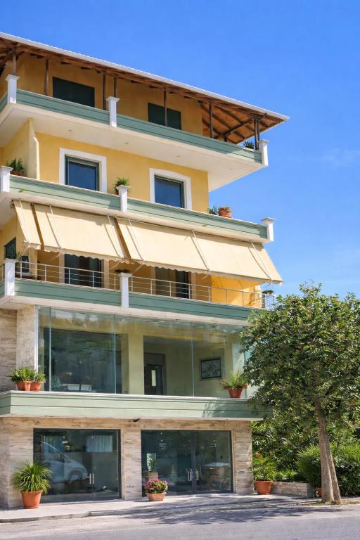 a large yellow building with a tree in front of it at Kapo Apartments in Gjirokastër