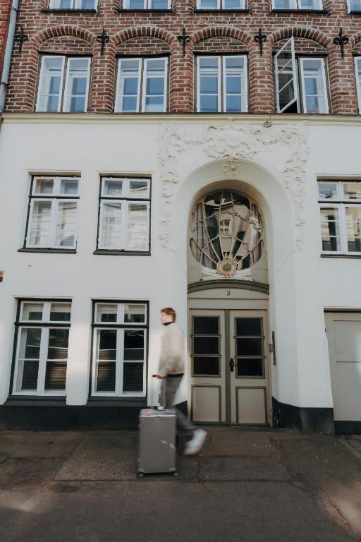 a man with a suitcase walking past a building at Apartments im Einhornhaus in Lübeck