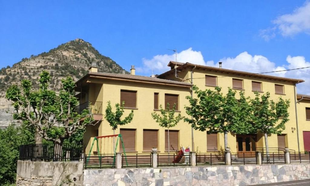 a yellow house with a mountain in the background at Apartamentos Ésera in Santa Liestra y San Quílez