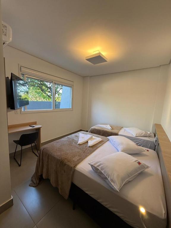 a bedroom with two beds and a desk and a window at Hotel Morais in Lagoa Vermelha