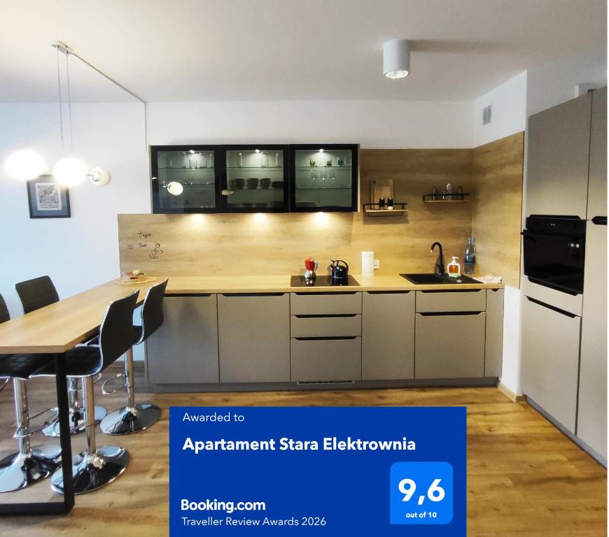 an open kitchen with a table and a refrigerator at Apartament Stara Elektownia z garażem in Zamość