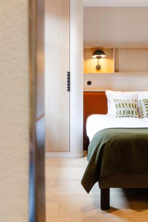 a bedroom with a bed with a green blanket at AUBERGE FRANKENBOURG in La Vancelle