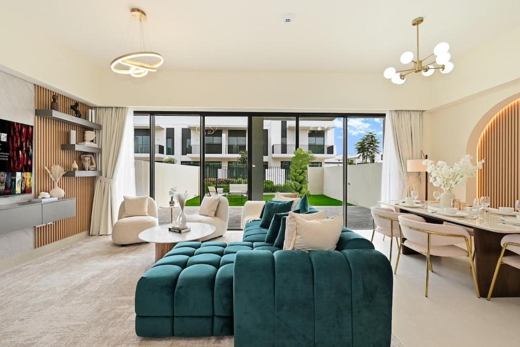 a living room with a green couch and a dining room at Warm and Cozy 4BR Villa with Pool Access in Dubai