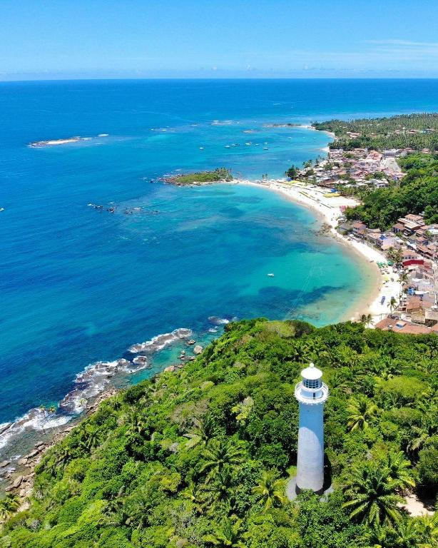 a lighthouse sitting on top of a hill next to a beach at Edifício AES Brasil in Cairu