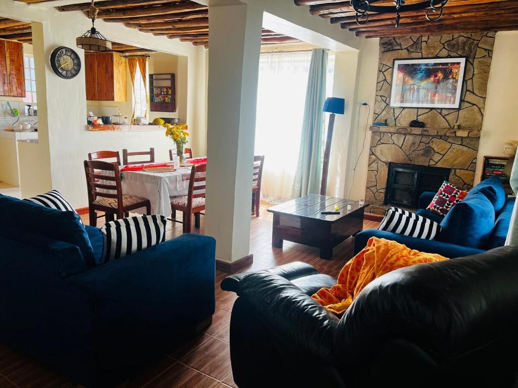 a living room with couches and a table and a kitchen at KFarm house in Kijabe