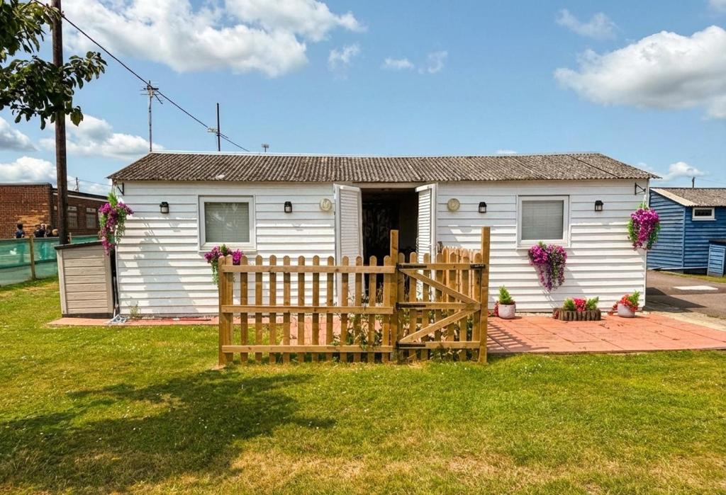 a white house with a wooden fence in front of it at Sun, Sand & Sheppey The Ultimate Escape in Leysdown-on-Sea