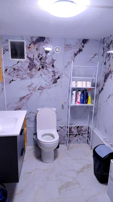 a bathroom with a white toilet and a marble wall at Le séjour in Champigny-sur-Marne