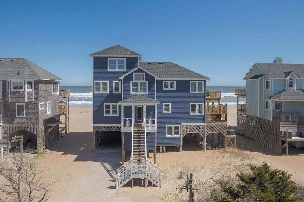 a blue house on the beach with condos at 7677 - Weathering Heights in Avon