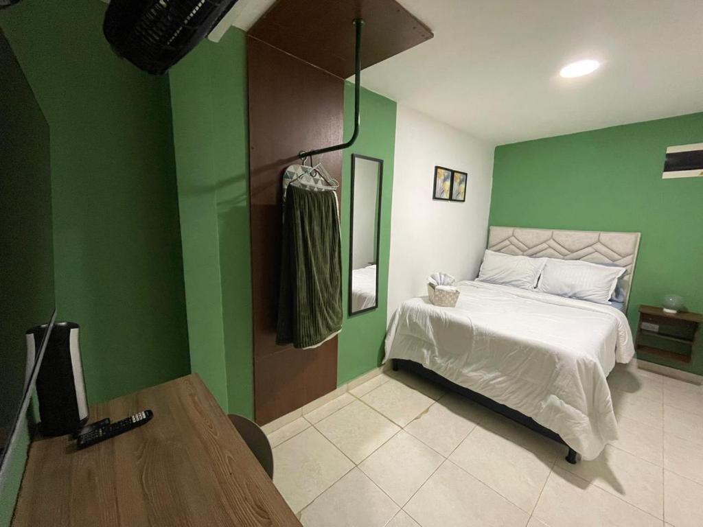 a bedroom with green walls and a bed and a table at Olivo House Casa Hotel in Envigado