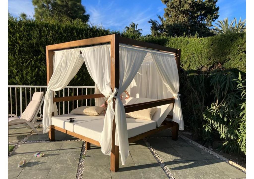 a canopy bed with white curtains on a patio at El Campirri in Daimés