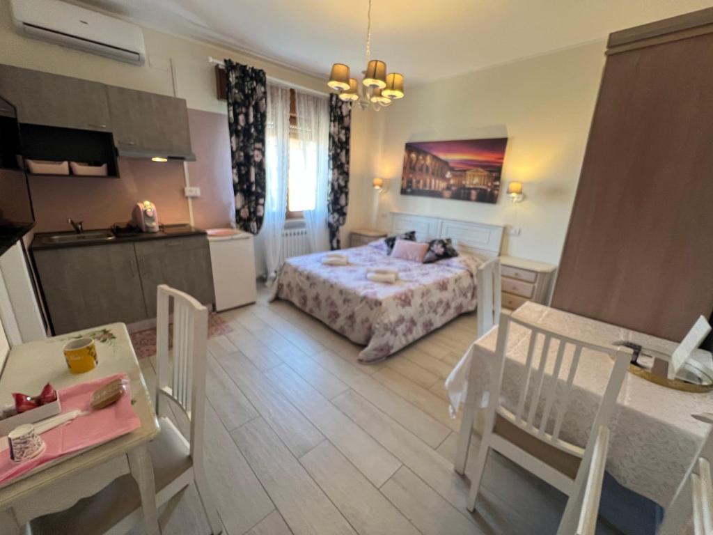 a bedroom with a bed and a table and a kitchen at Monolocale Pink Borgo Roma GB Rossi friendly Verona in Verona