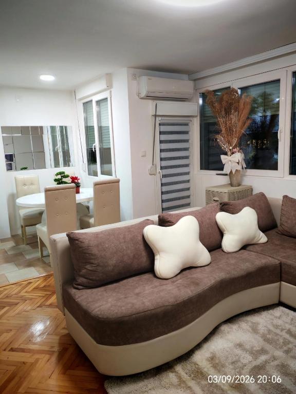 a living room with a brown couch with white pillows at Apartman ANA in Pirot
