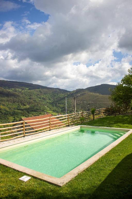 a swimming pool in the grass next to a fence at Refugio dos Cartolas - Mountain Retreat in São Mamede
