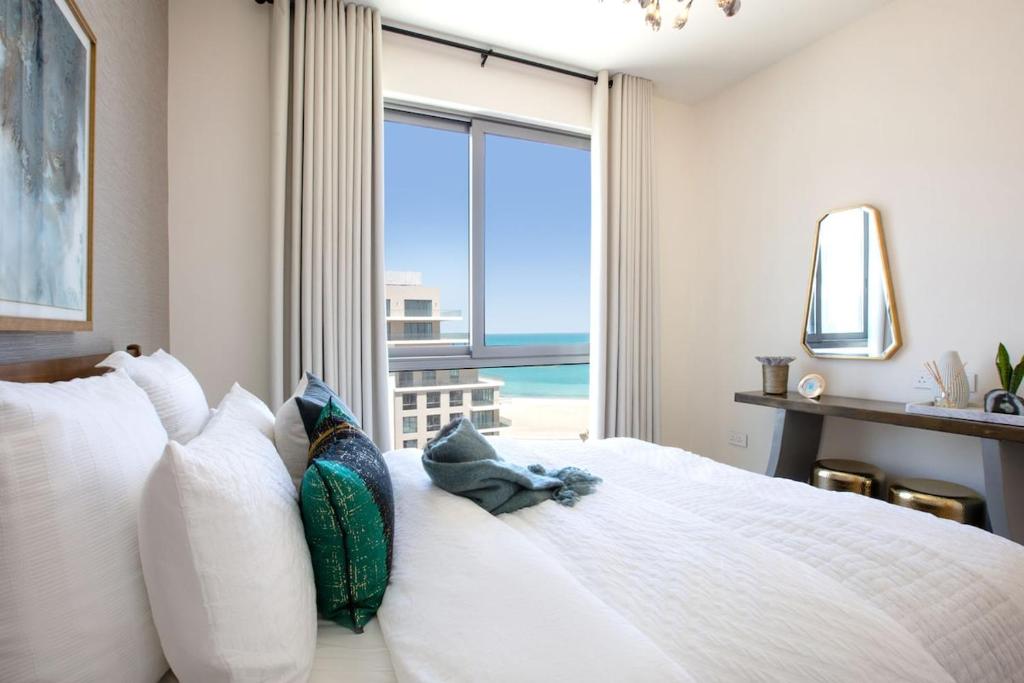 una camera da letto con un letto grande con una grande finestra di Marassi Shores a Amwaj Island
