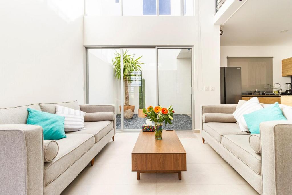 a living room with two couches and a table with flowers at Quiet and comfortable space in Aguascalientes