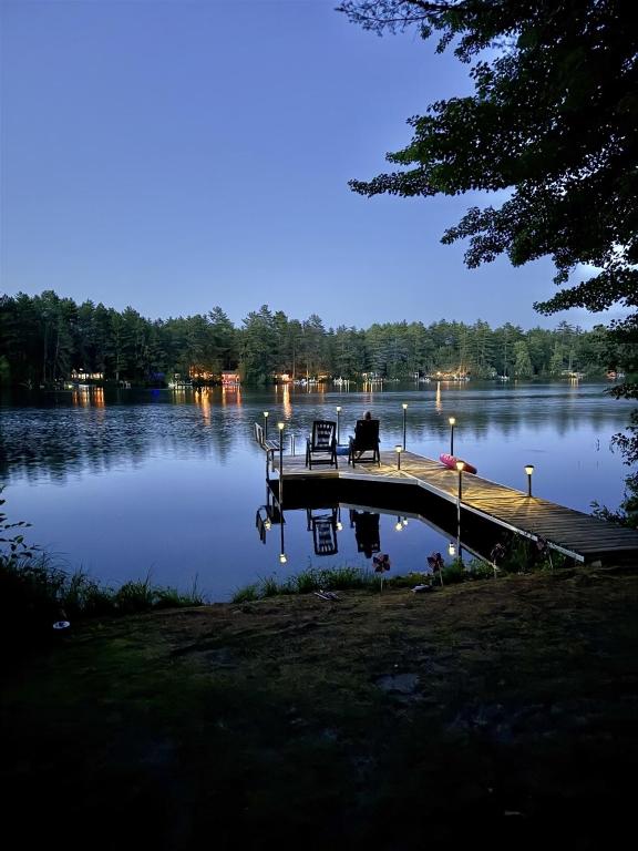 a person sitting on a bench on a dock on a lake at UPTA CAMP LIMIT 8 cabin in West Baldwin
