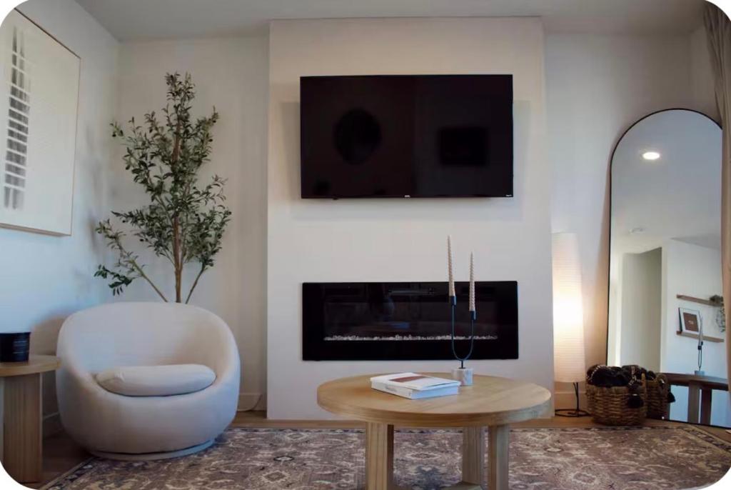 a living room with a white chair and a fireplace at Brùn House in Fort Saint John