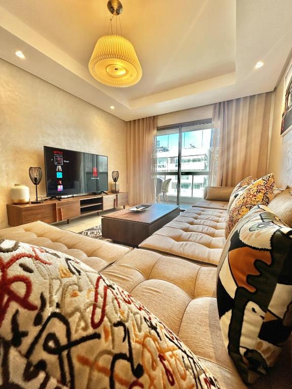 a living room with a large couch and a television at Spacious Studio with Pool & Wi-Fi in Aïn Harrouda
