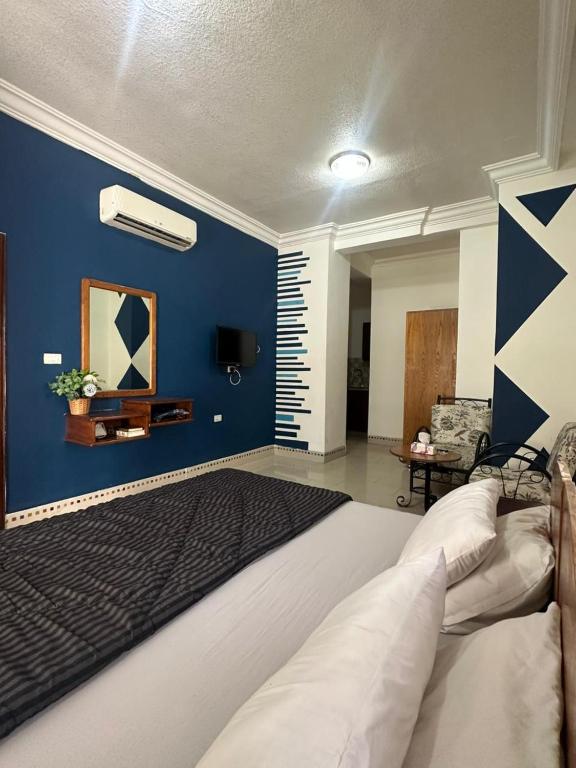 a bedroom with a large bed with a blue wall at Al Majd Hotel in Amman