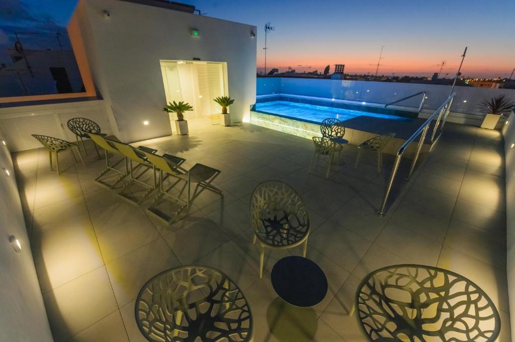 a balcony with chairs and a swimming pool at night at Apartamentos Aires de Conil in Conil de la Frontera