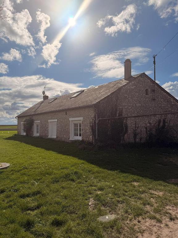 an old brick building with the sun in the sky at Escale à Rosay in Theuville