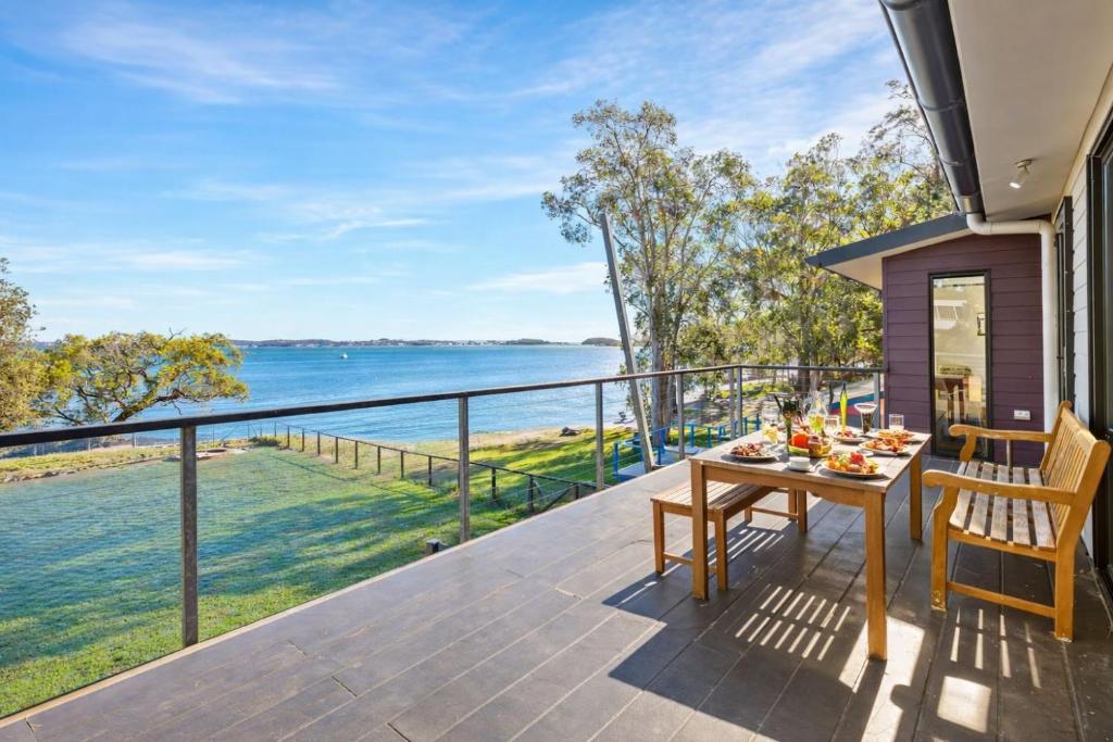 a deck with a table and chairs and a view of the water at Pindimar Beach Sanctuary Absolute Beachfront in Pindimar