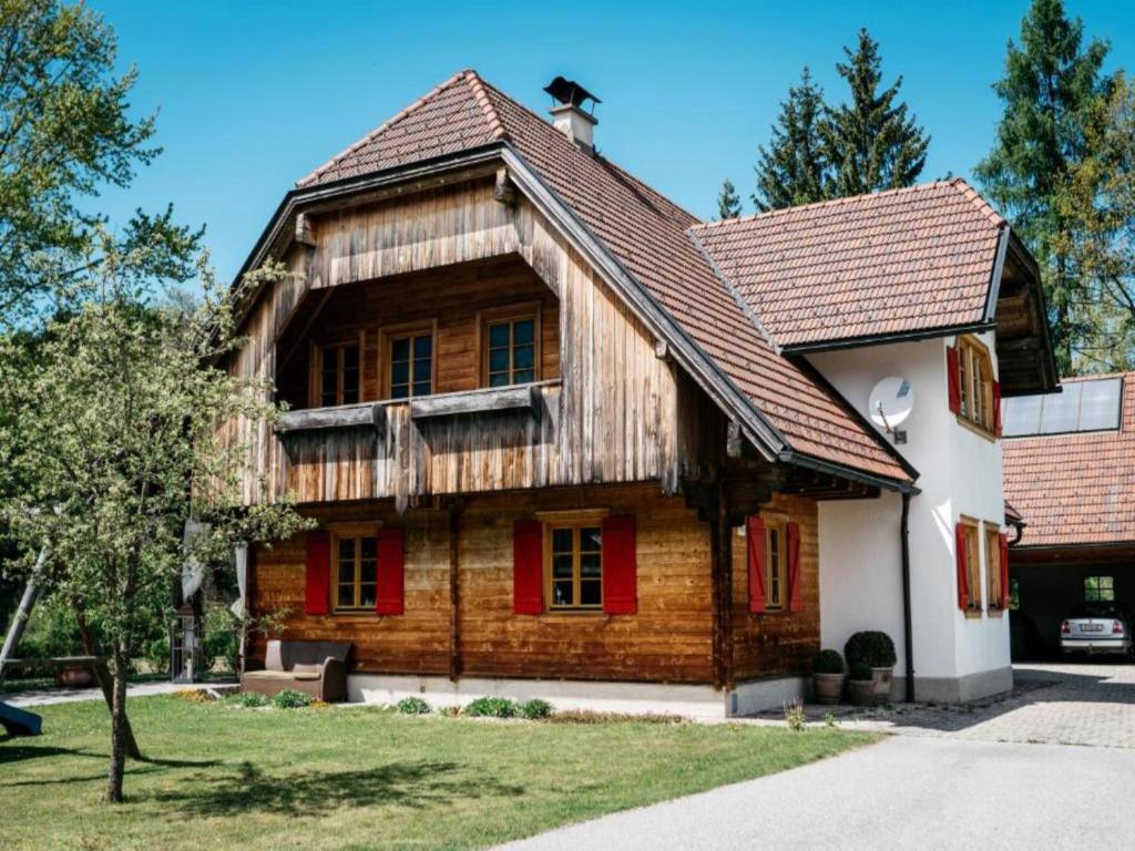 an old wooden house with red windows and a roof at Feistritz Berg und See in Feistritz ob Bleiburg