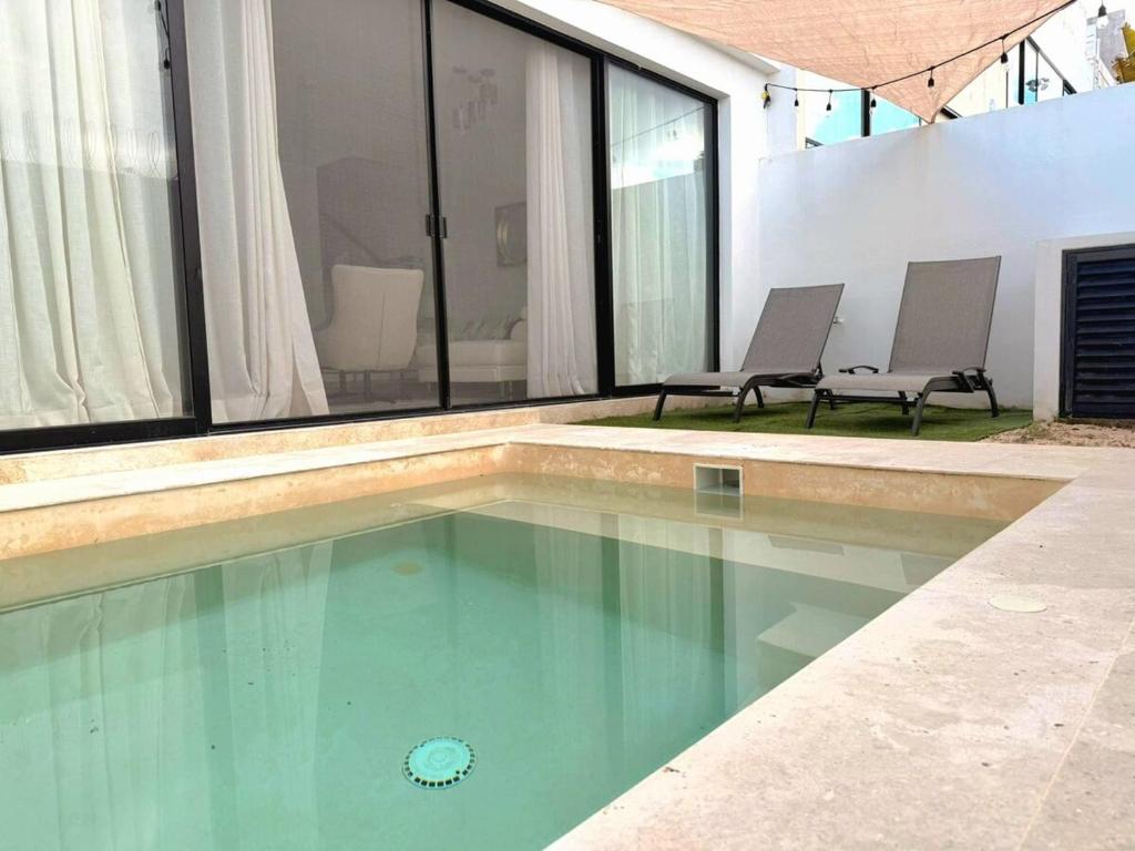 a swimming pool with two chairs in a house at Cancún Arbolada Huayacan in Cancún