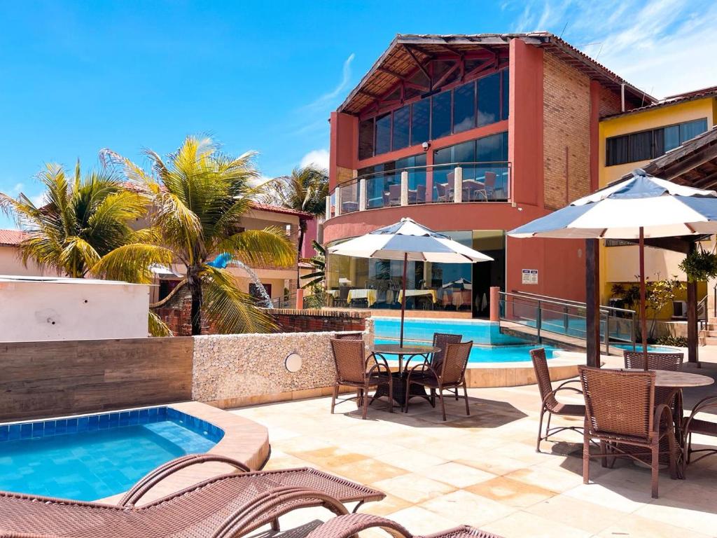 a resort with a pool and tables and chairs at Planet Dunas in Aquiraz
