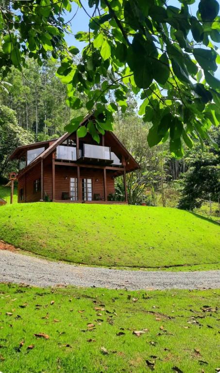 a house on top of a grassy hill with a gravel road at Chalé Recanto do Vale pomerode in Pomerode