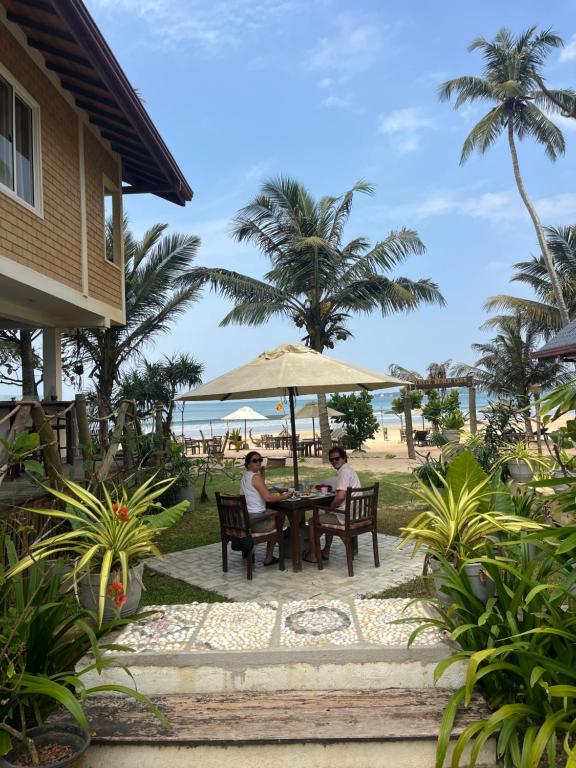 two people sitting at a table under an umbrella at Beach Garden in Weligama