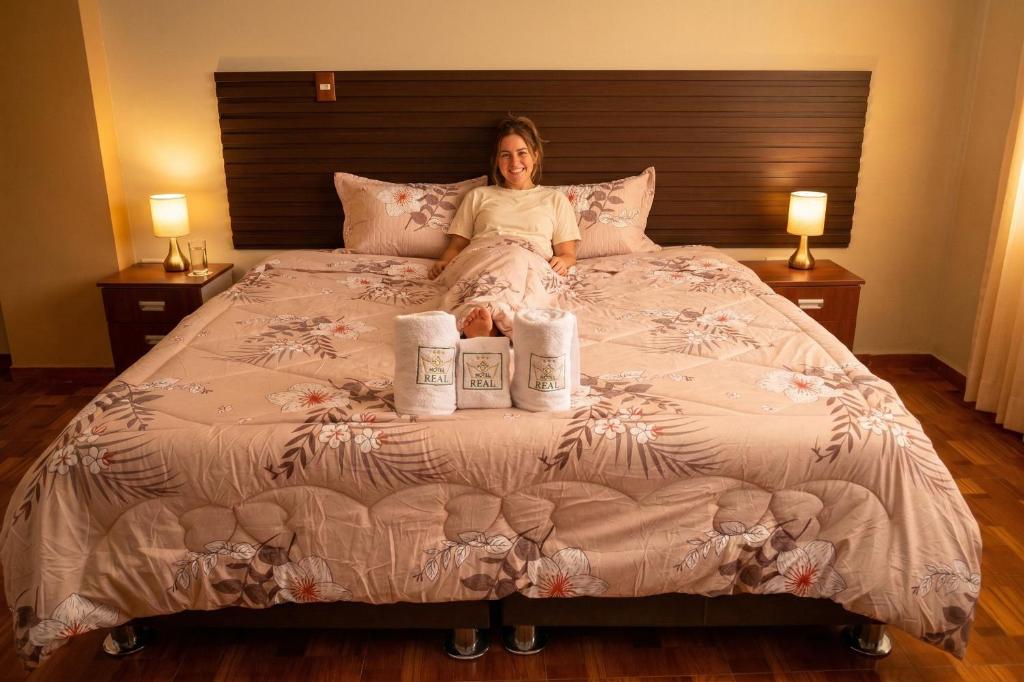 a woman sitting on a bed with three rolls of paper towels at Gran Hotel Real in Huancayo