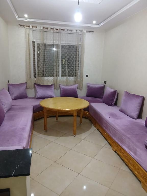 a living room with purple couches and a wooden table at Appartement hay lmatar in Nador